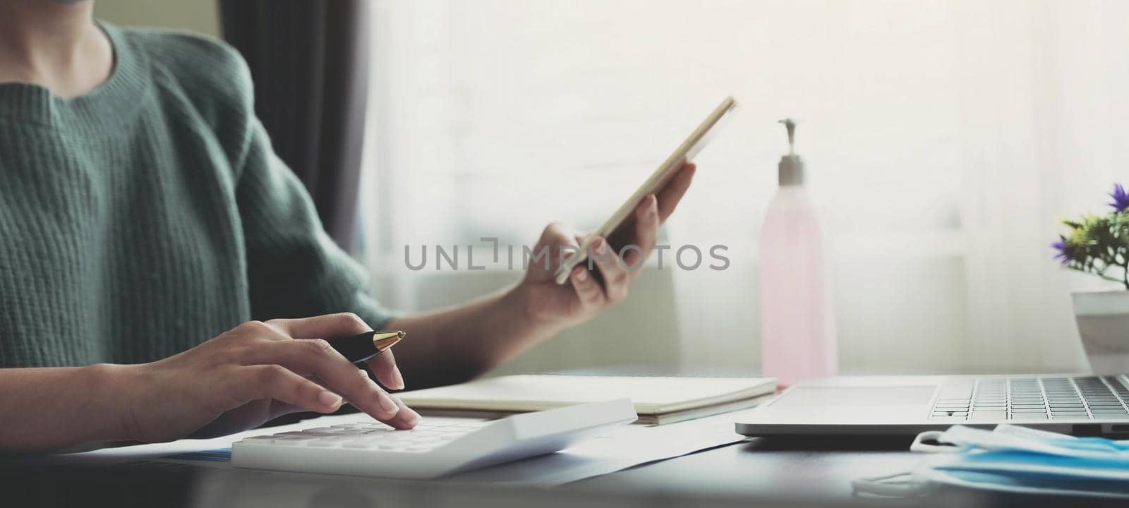 accounting, taxes and finances concept - woman with smartphone and calculator wearing face protective medical mask for protection from virus disease at home..