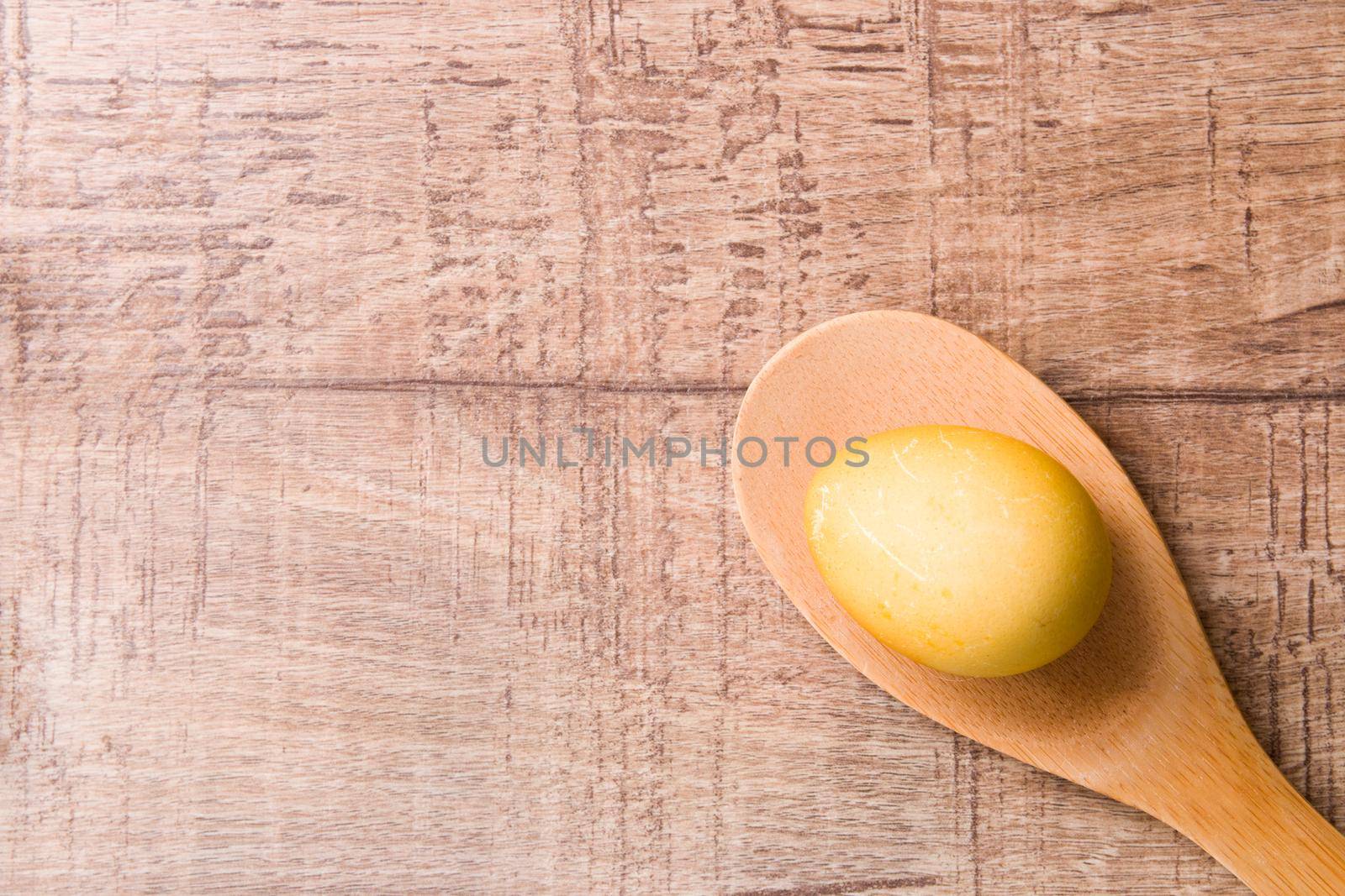 yellow egg on wooden spoon wooden background, copy space, easter background