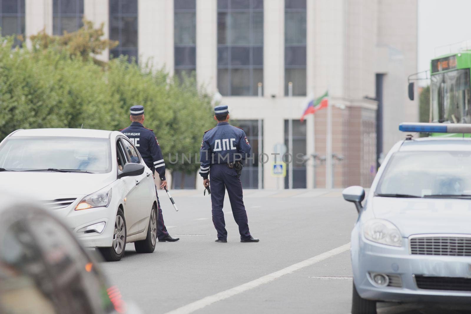 Russian officers of the road police service with striped wands watching the city road. Wide shot