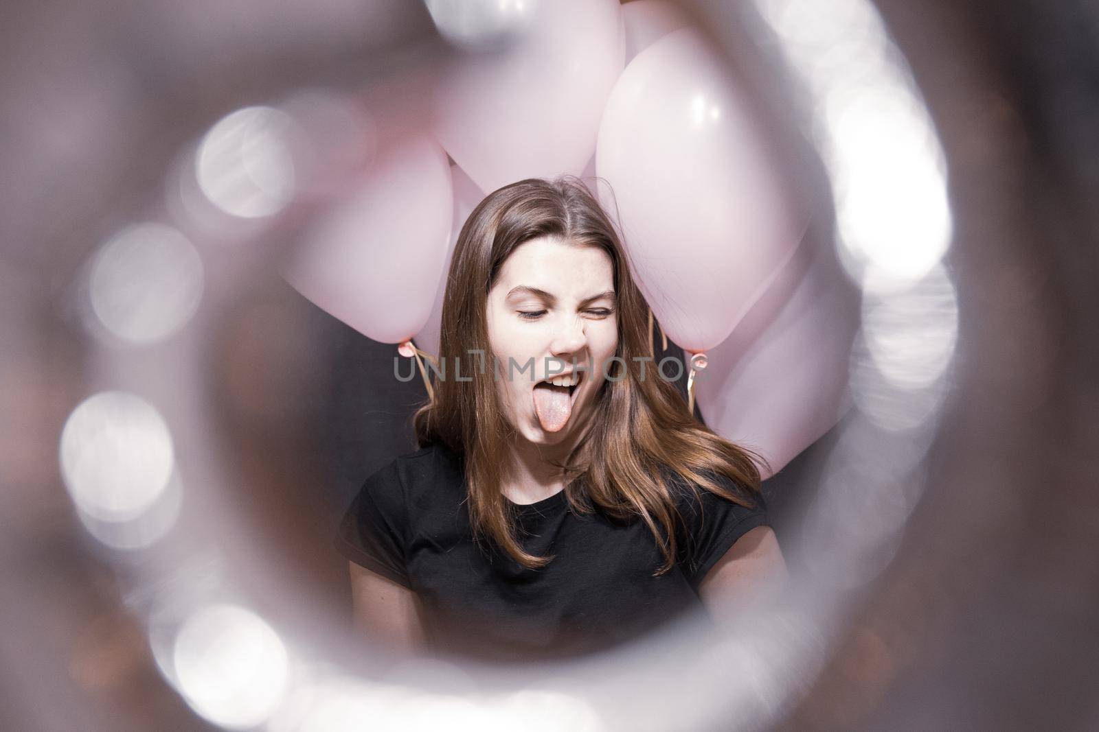 View through the tunnel. The face of a pretty girl with an emotion of joy that holds pink balloons on her birthday by lunarts