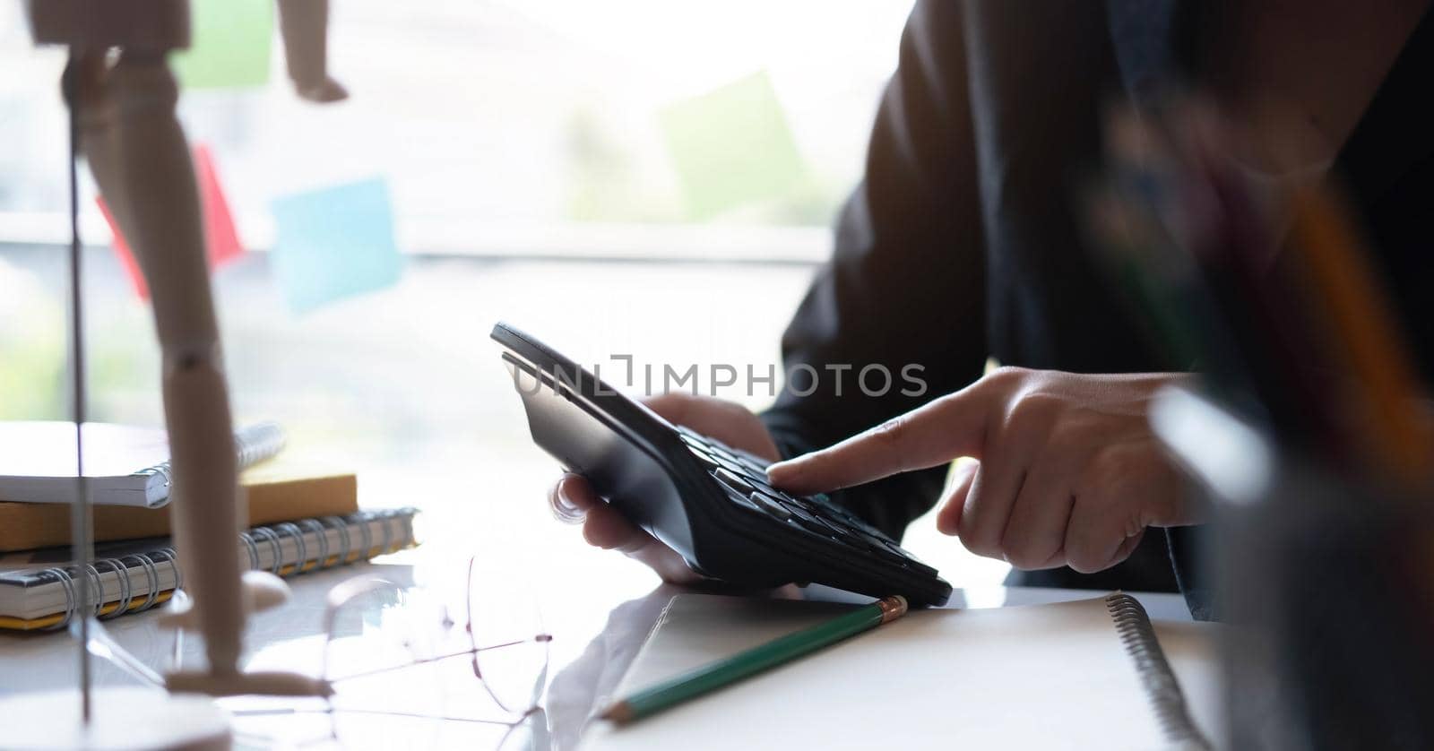 Businesswoman working about calculating budget income stats using calculator holding a pen pointing at the graph at the office. by wichayada