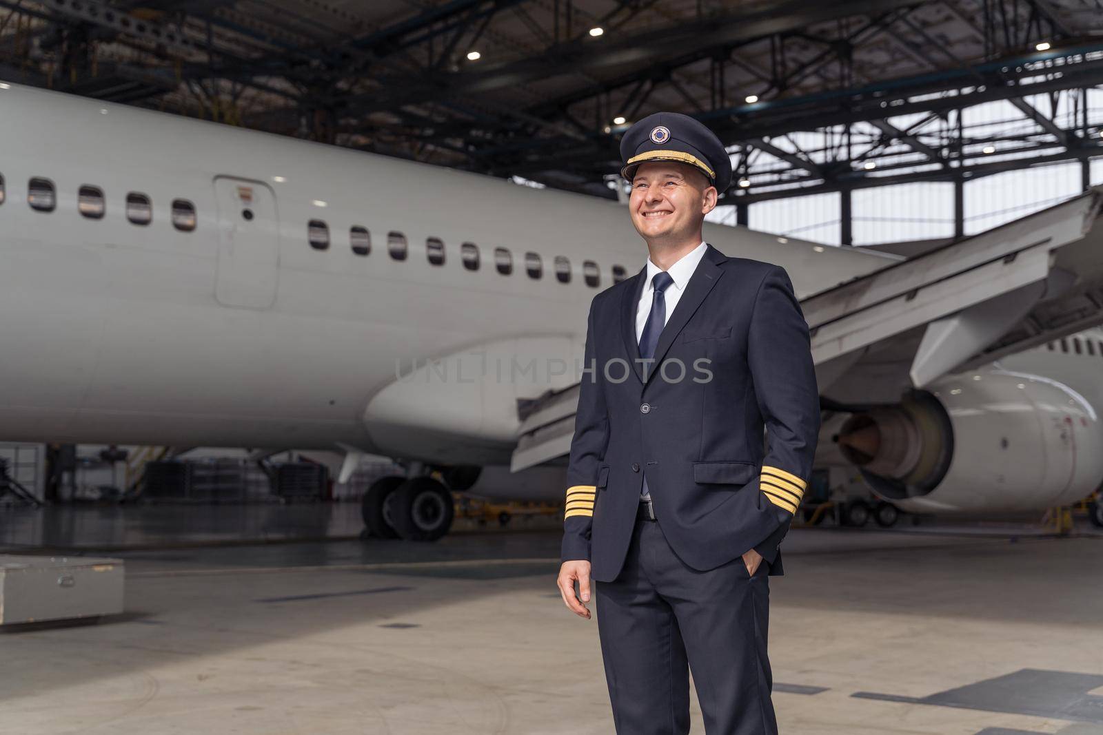 Handsome pilot posing against the backdrop of the aircraft in the hangar by Yaroslav_astakhov