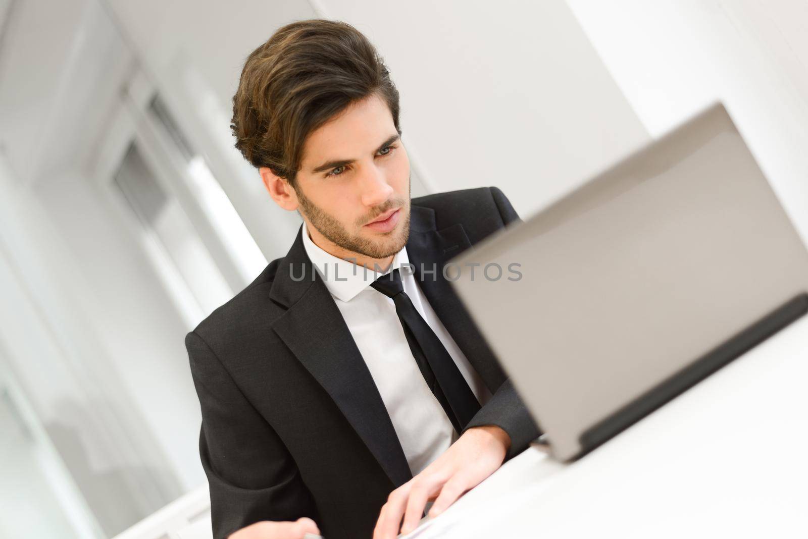 Portrait of a smiling businessman sitting at his laptop and working in his office