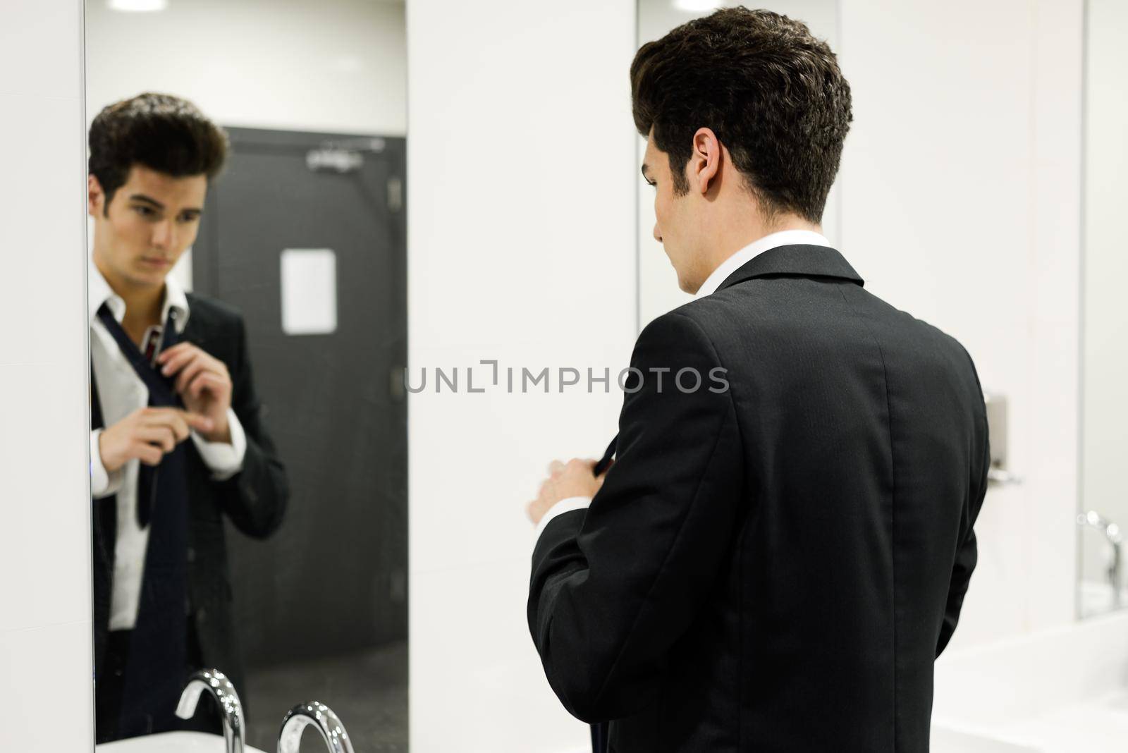 Portrait of a man getting dressed in a public restroom with mirror