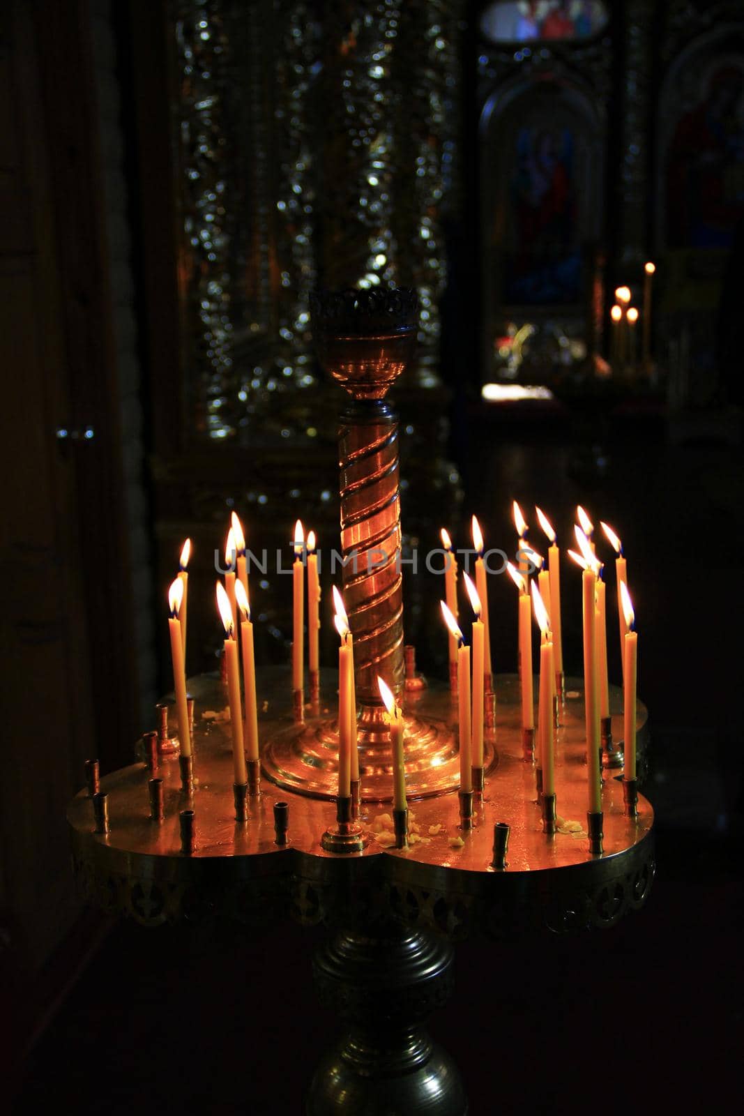 church candles on candlesticks in church burn in darkness