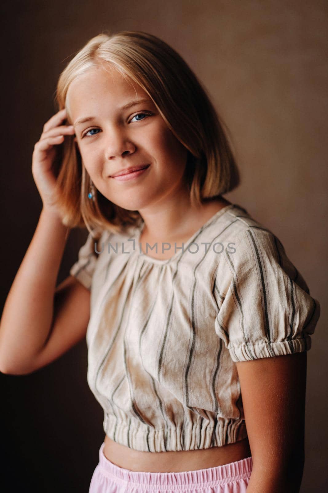 A happy child, a little girl in a gray T-shirt on a beige background.