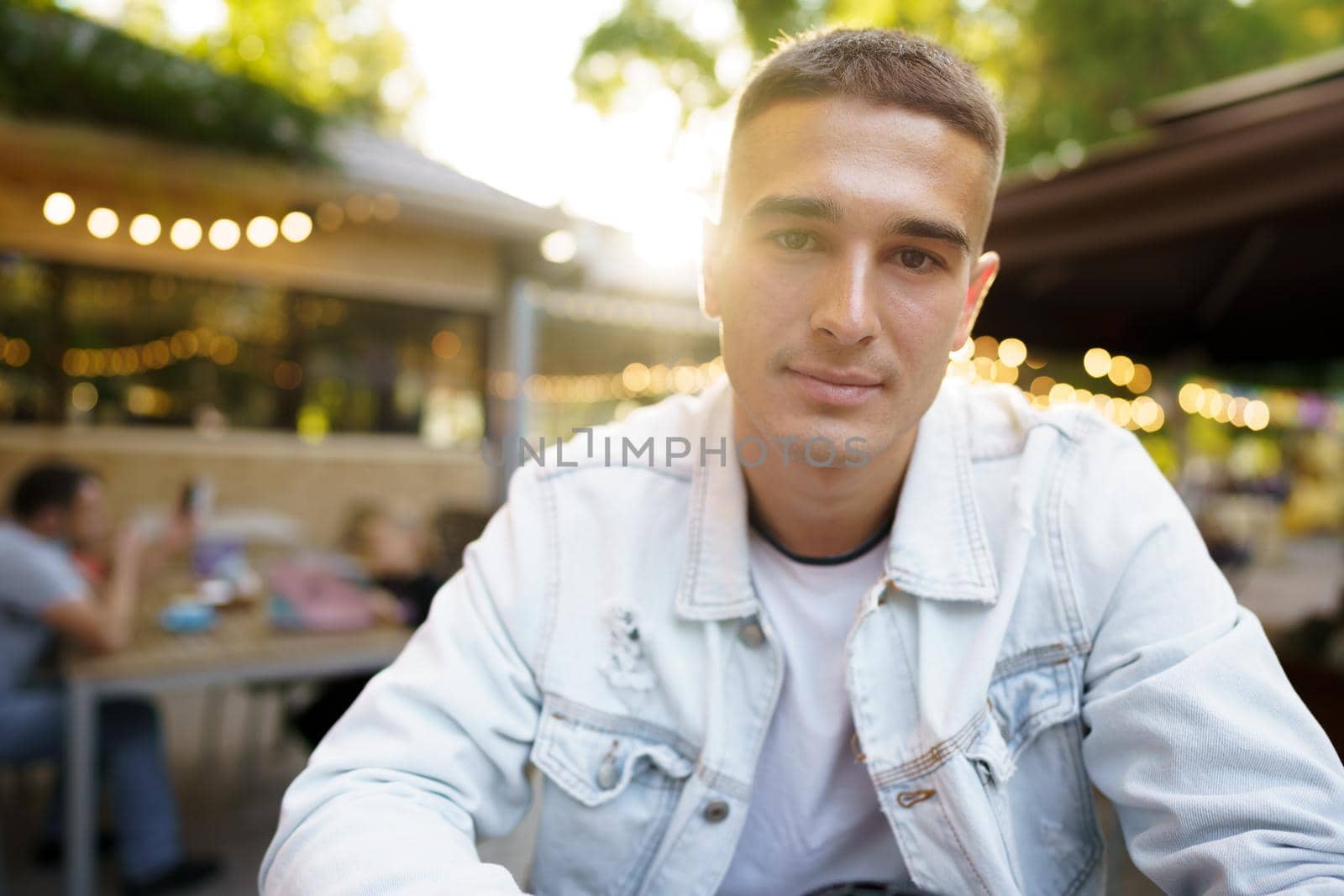 Portrait of a handsome young man sitting in outdoor cafe, close up