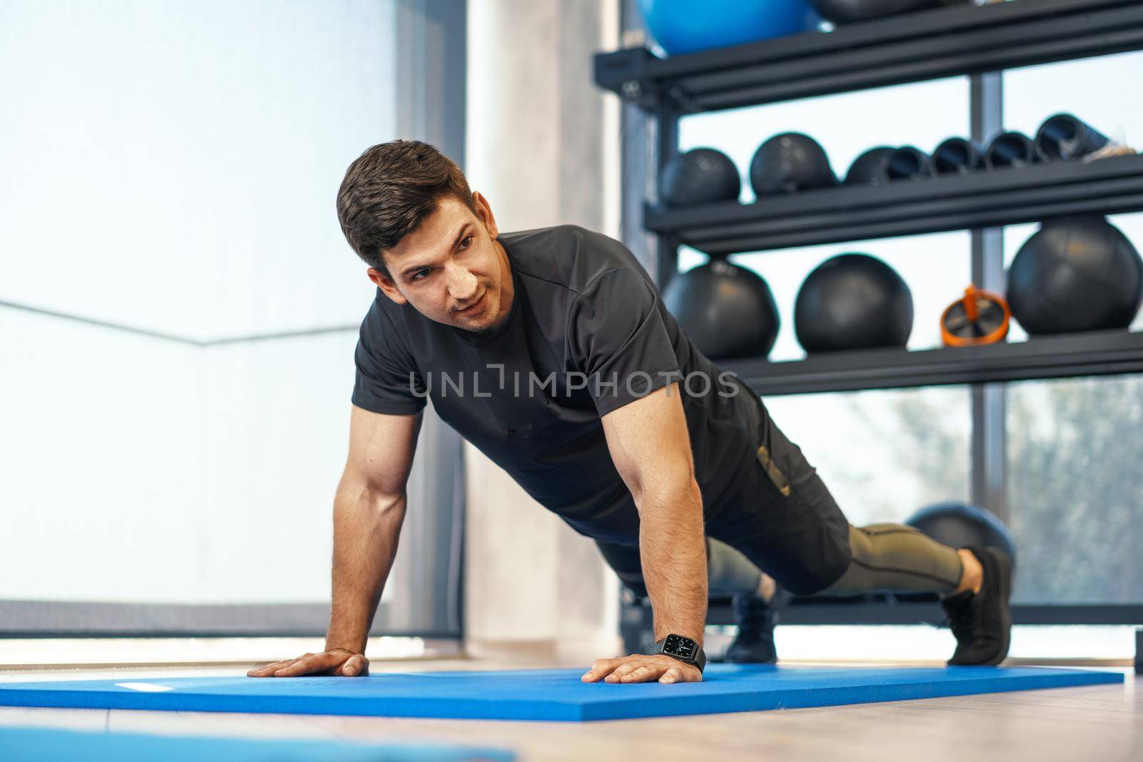 Young athletic man doing push-ups in a gym, close up photo