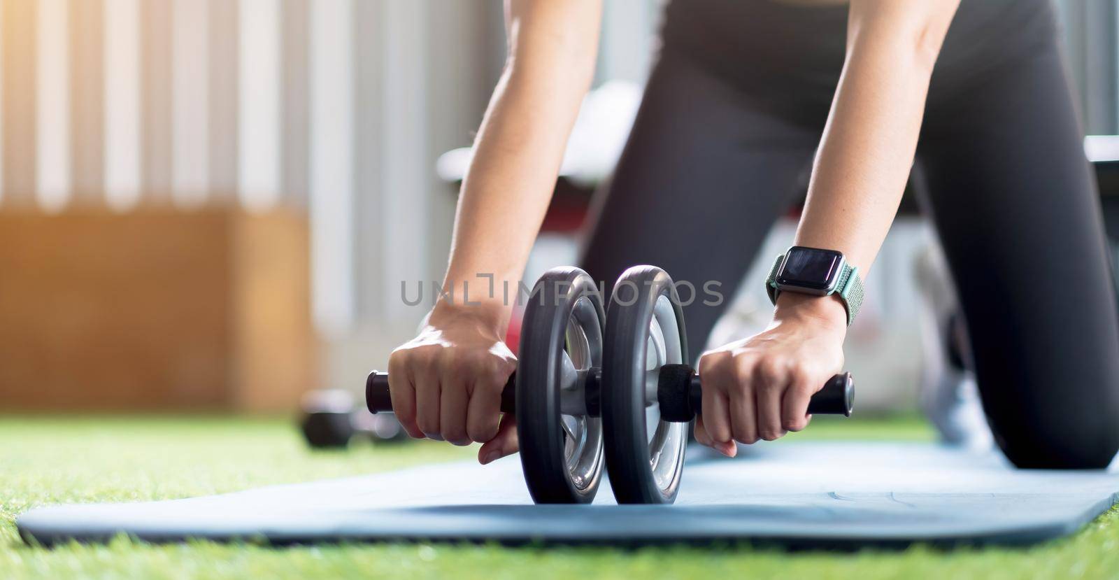 Hand women does the exercises with Ab Wheel in the gym. Sports concept, fat burning and a healthy lifestyle. by wichayada