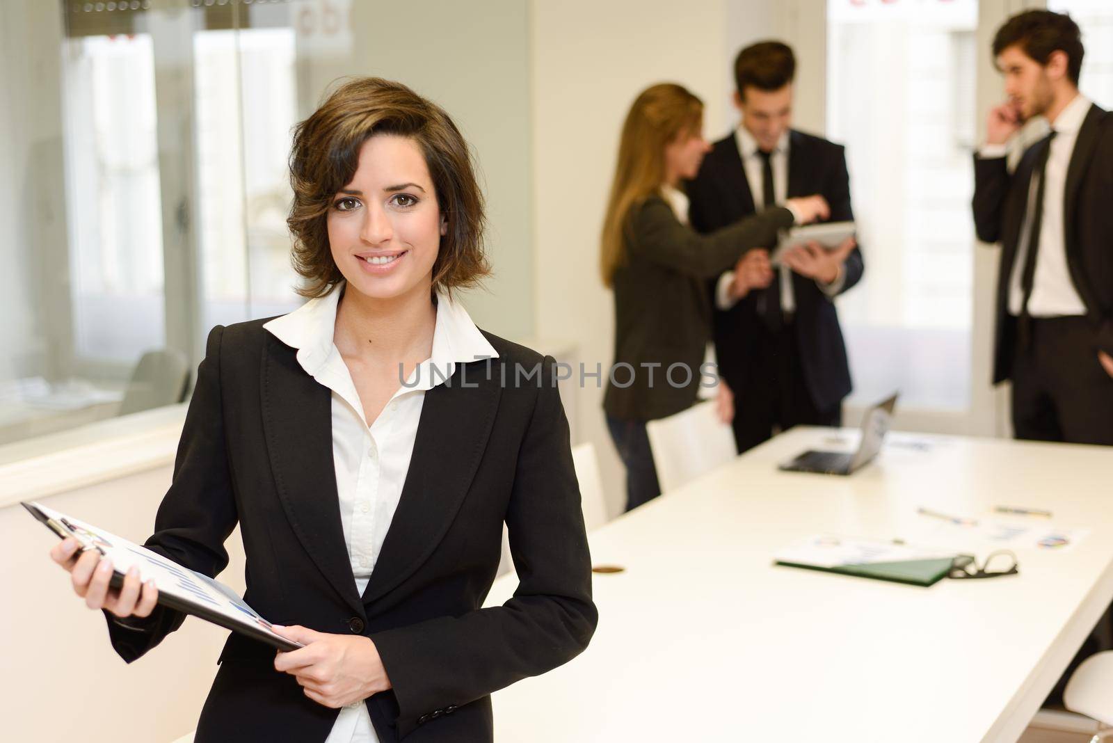 Image of business leader looking at camera in working environment. Woman with folder in her hands