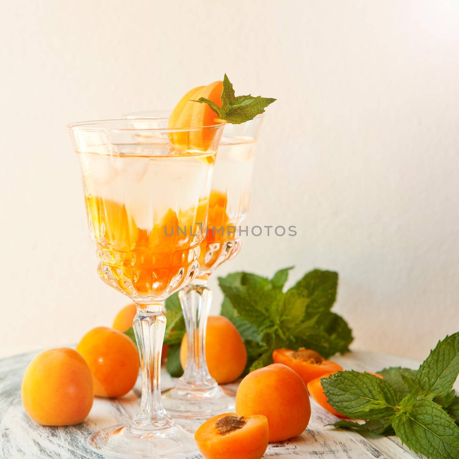 Summer drinks, mint apricot cocktails with ice in glasses. Refreshing summer homemade Alcoholic or non-alcoholic cocktails or Detox infused flavored water by julija