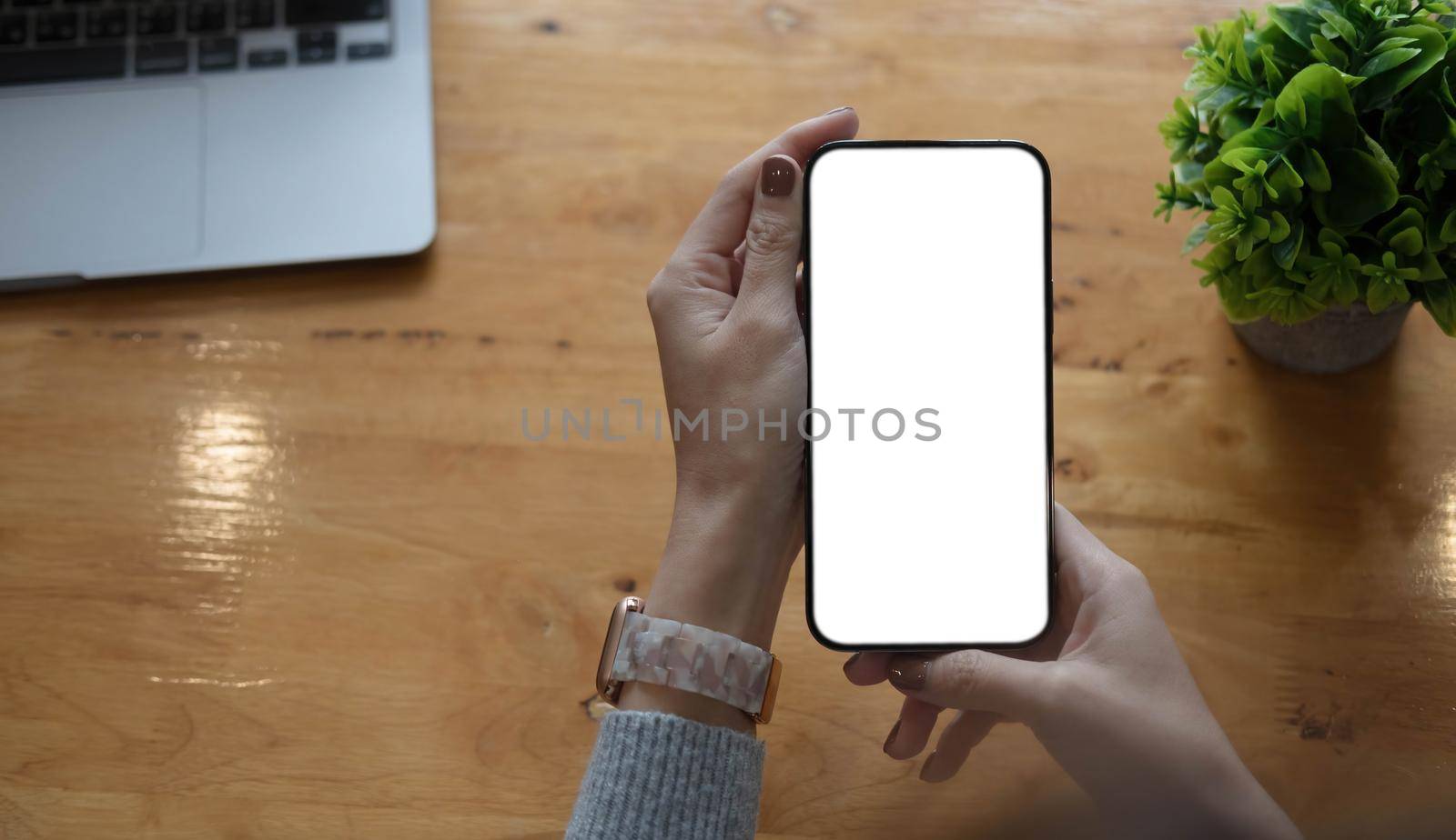 Mockup image blank white screen cell phone.women hand holding texting using mobile on desk at home office. by wichayada