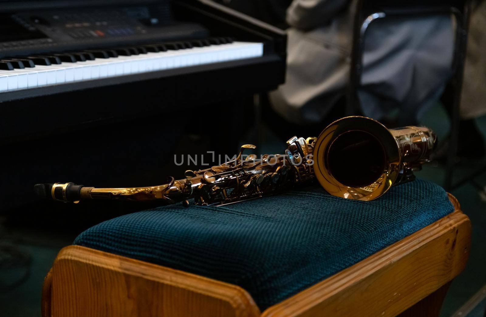 Close-up on a saxophone, which lies on a soft chair. by lunarts