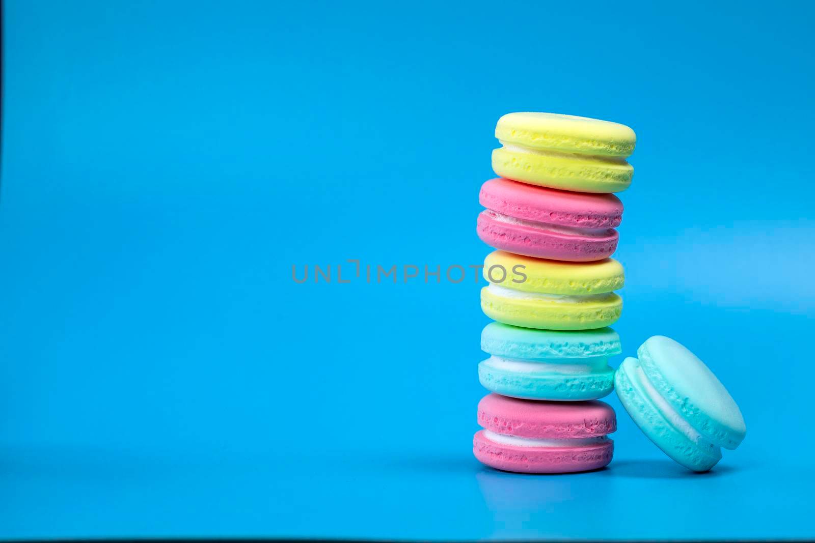 Pile of fresh baked colorful French macaroons on blue background , copy space banner. dessert,cookie,cake concept space for text