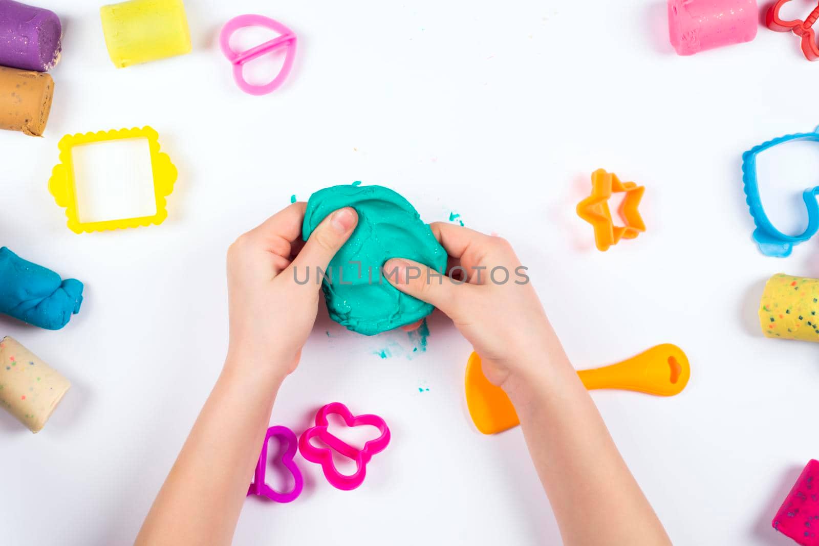Little girl play with modeling clay on white background. Top view. Home Education game with clay. Early development concept
