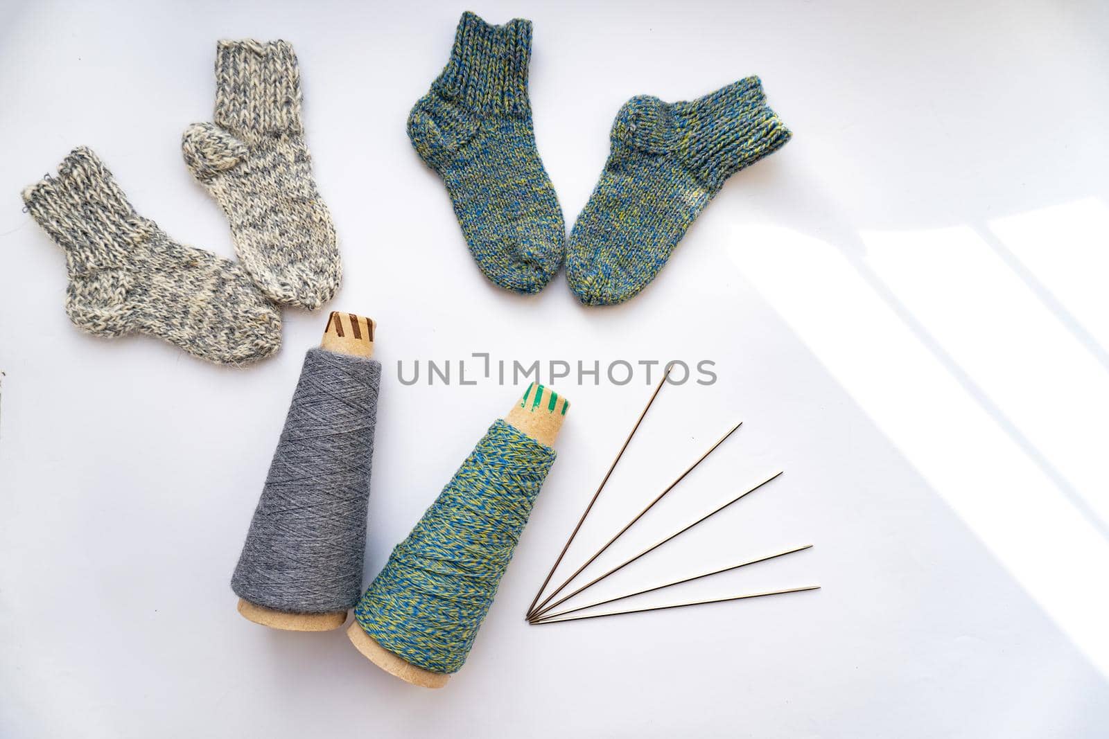 Socks, thread, needles are on white background with shadows, knitting concept.