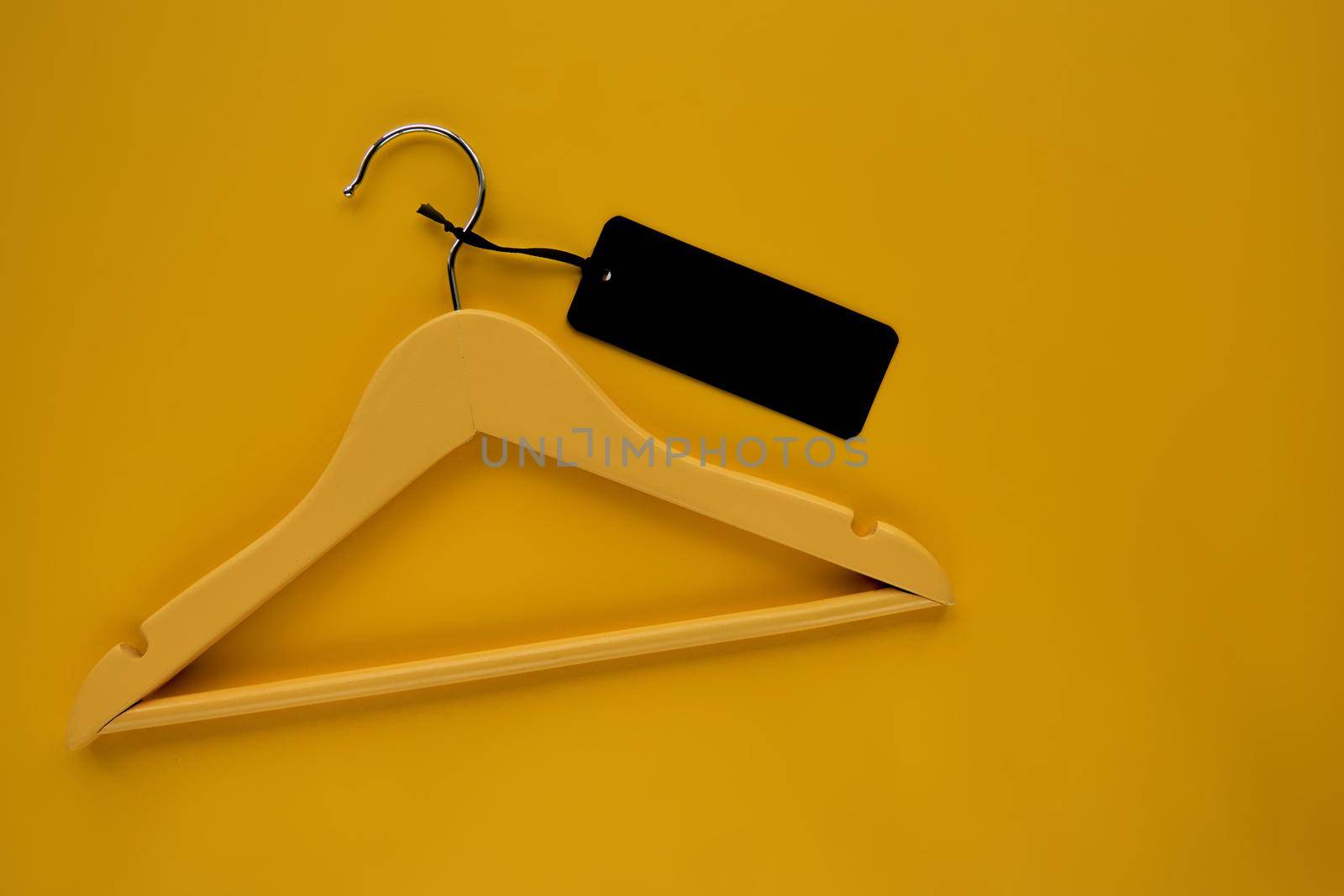 Wooden Coat hanger with black paper label isolated on yellow paper background. Clothing tag, label blank mockup template, to place your design. Black friday final sale banner by OneWellStyudio