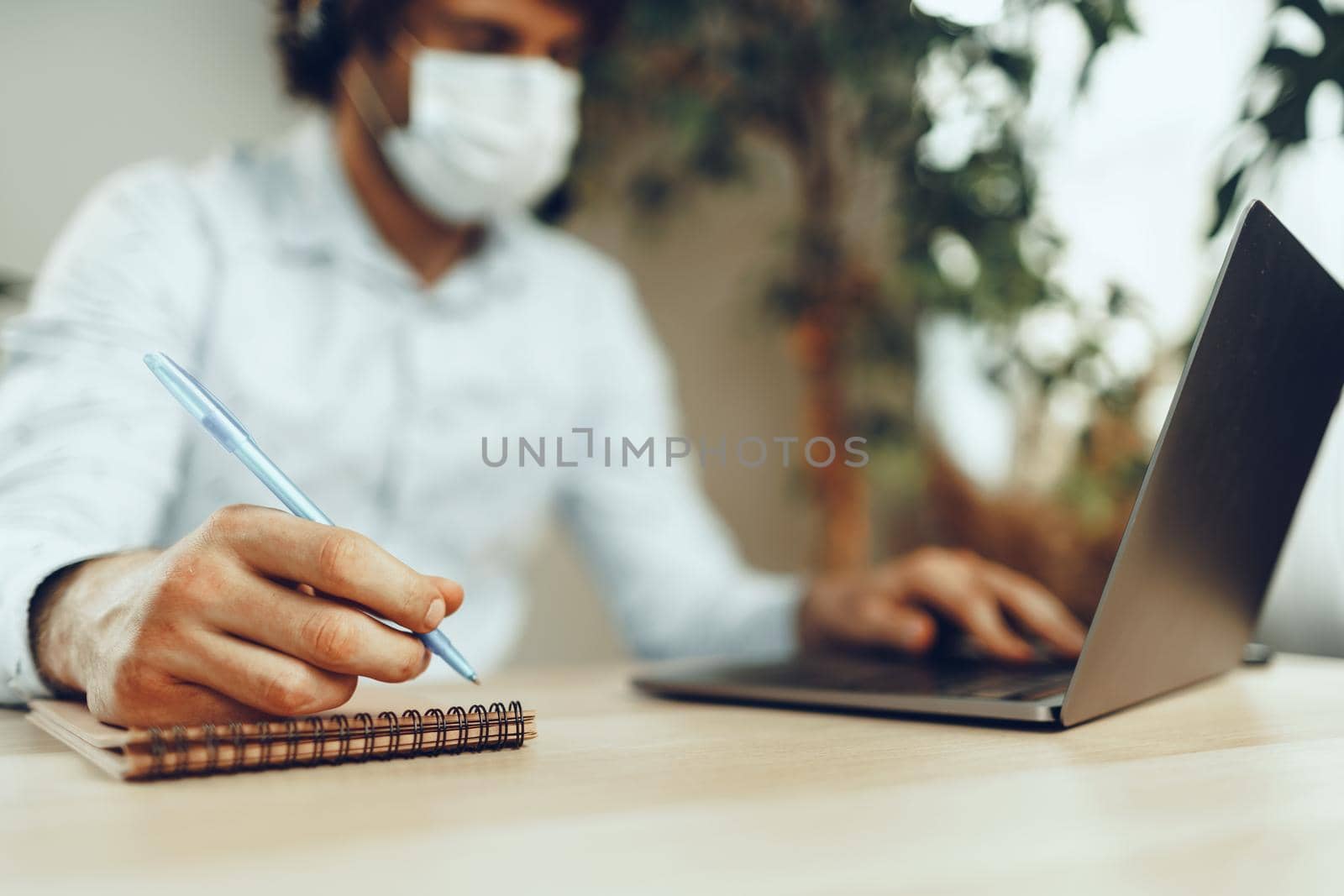 Man in medical mask working from home while coronavirus quarantine 2020