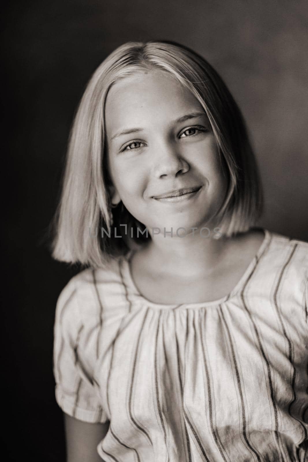 A happy child, a little girl in a gray T-shirt on a beige background. black and white photo.