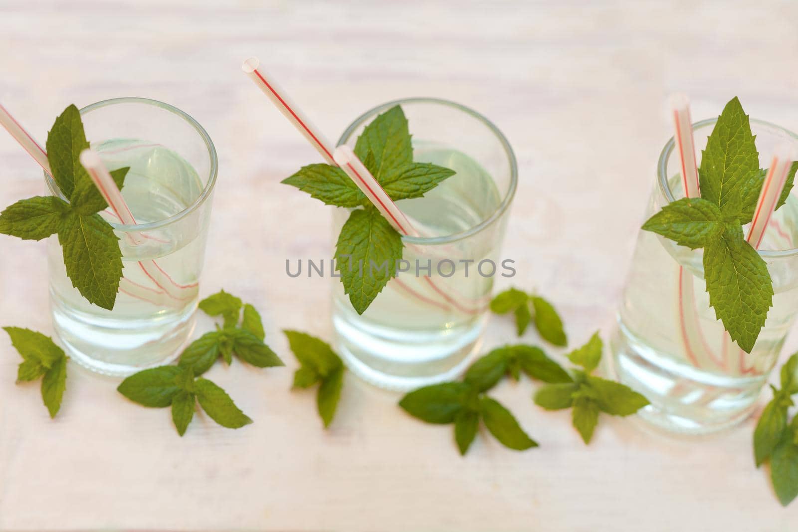 set of summer healthy homemade citrus lemonade infused water drink, mint leaves in glass on grey background. Close up mojito coctail. Selective focus.