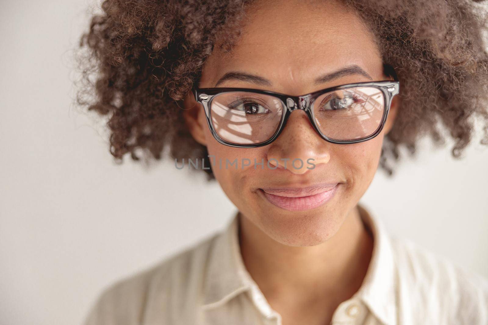 Close up of smiling Afro American woman wearing glasses and looking at camera, isolated on grey background