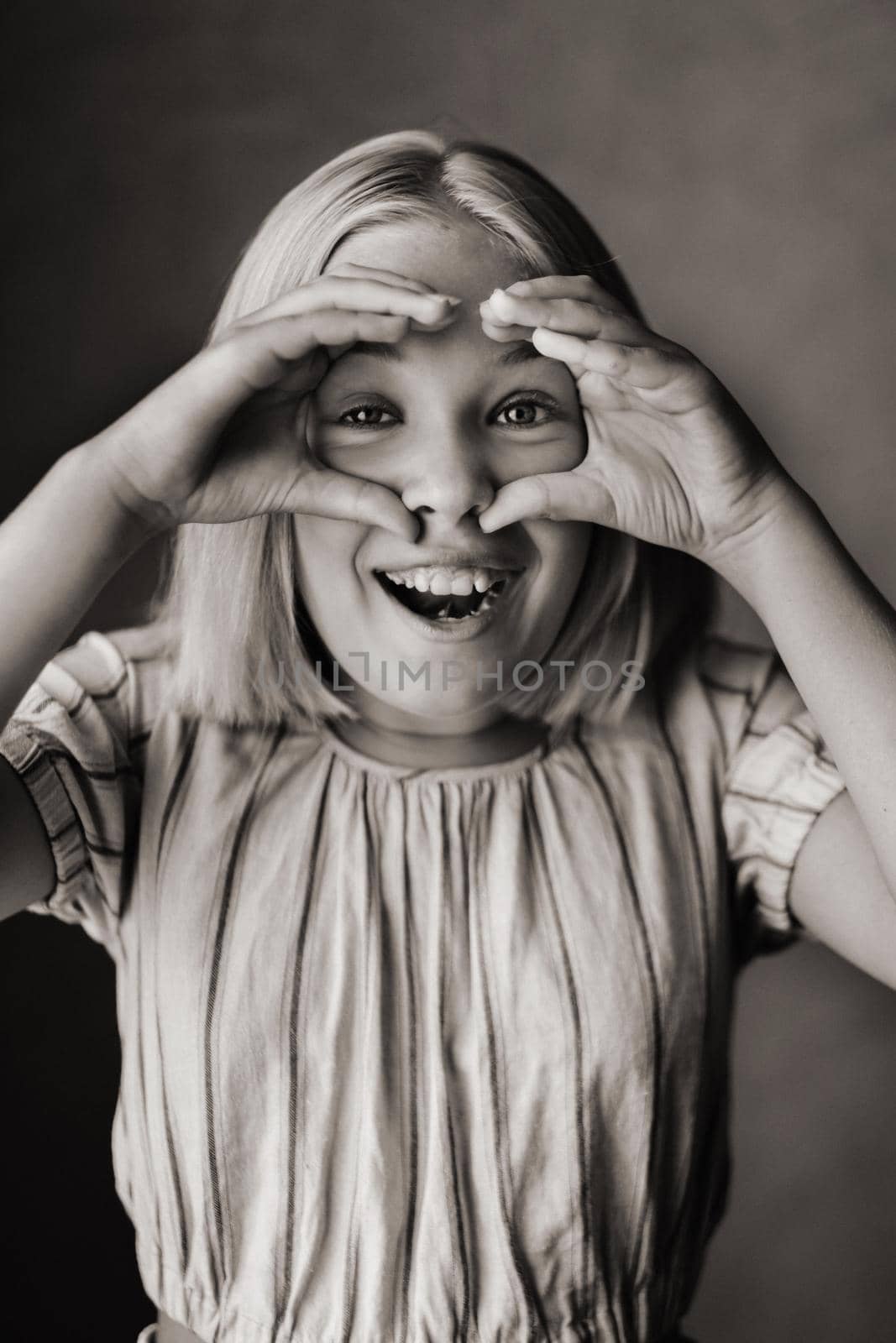 A happy child, a little girl in a gray T-shirt on a beige background. black and white photo.