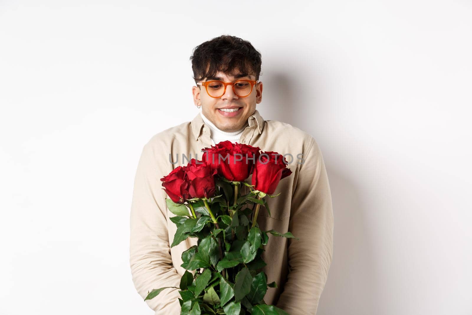 Cheerful gay man receive red roses from boyfriend, looking excited and smiling, having romantic date on Valentines day with lover, standing over white background by Benzoix