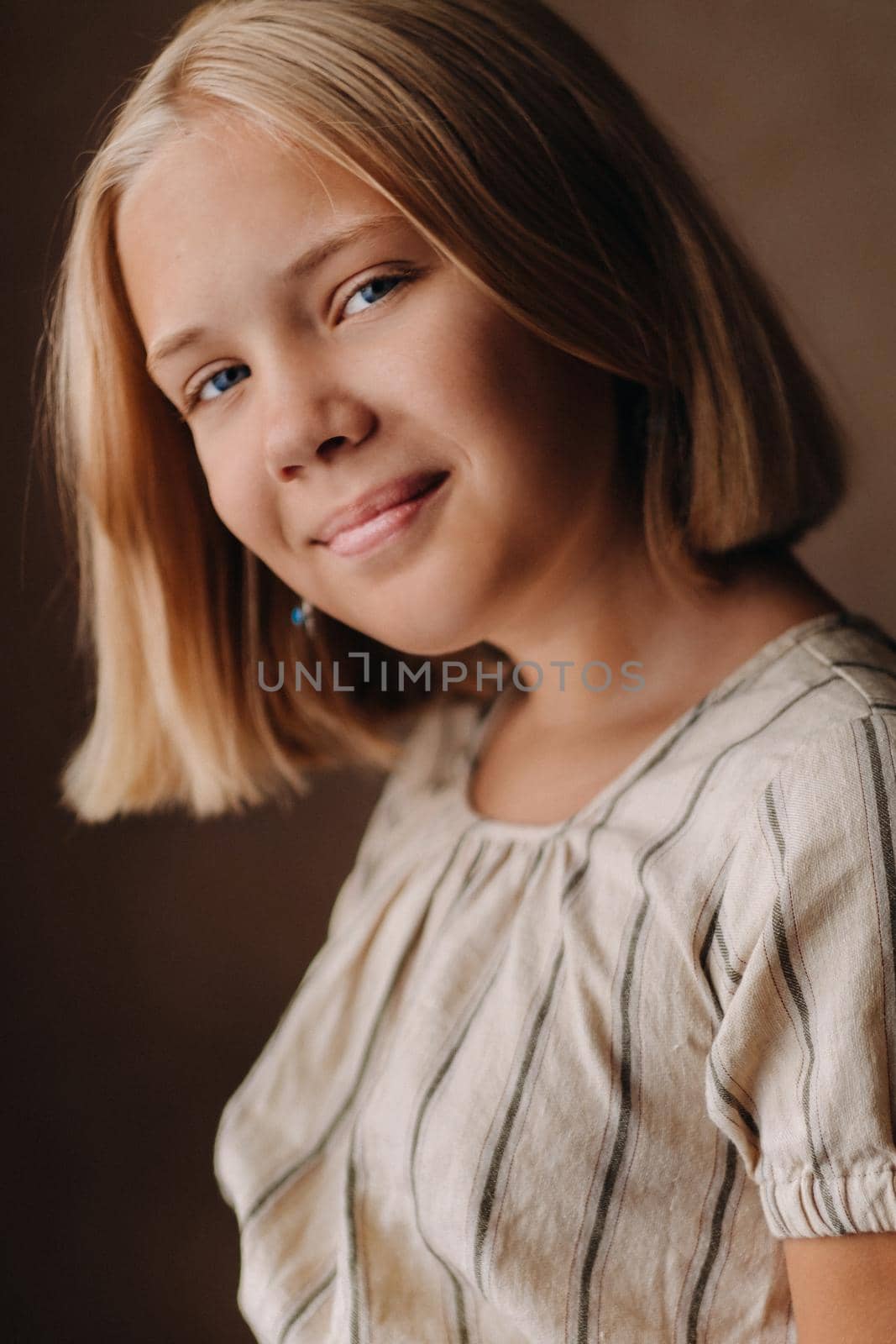 A happy child, a little girl in a gray T-shirt on a beige background.