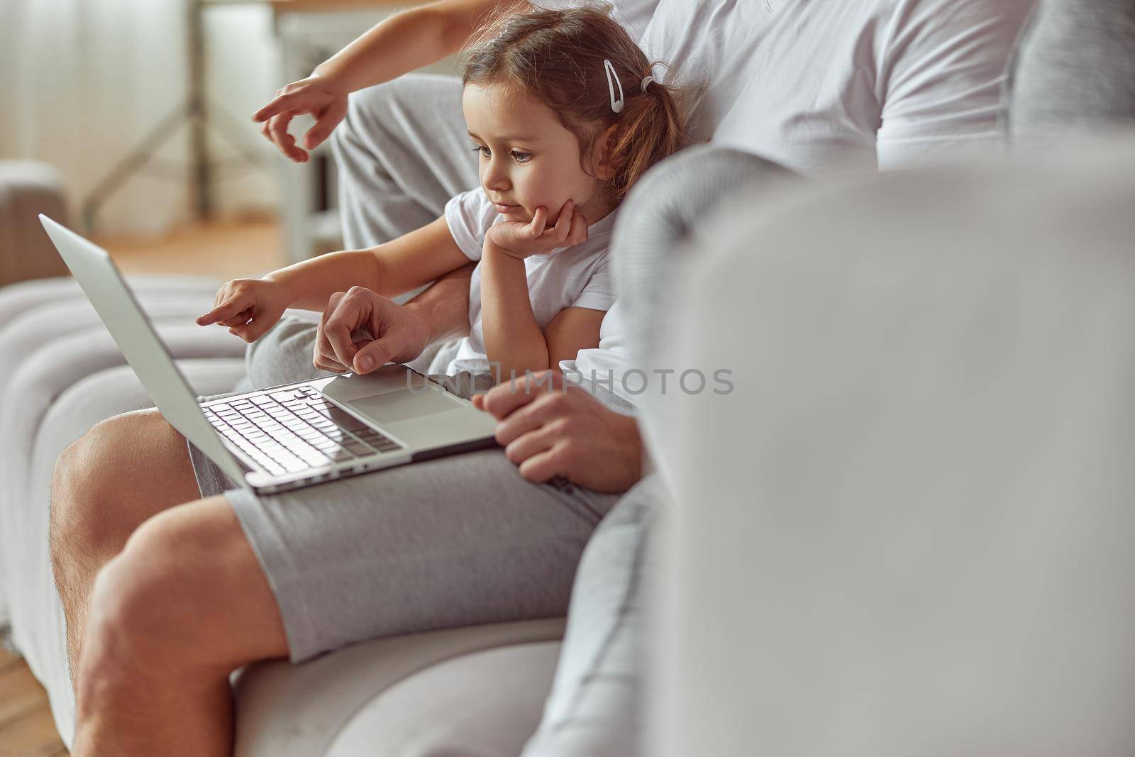 Curious girl watching video with family on laptop by Yaroslav_astakhov