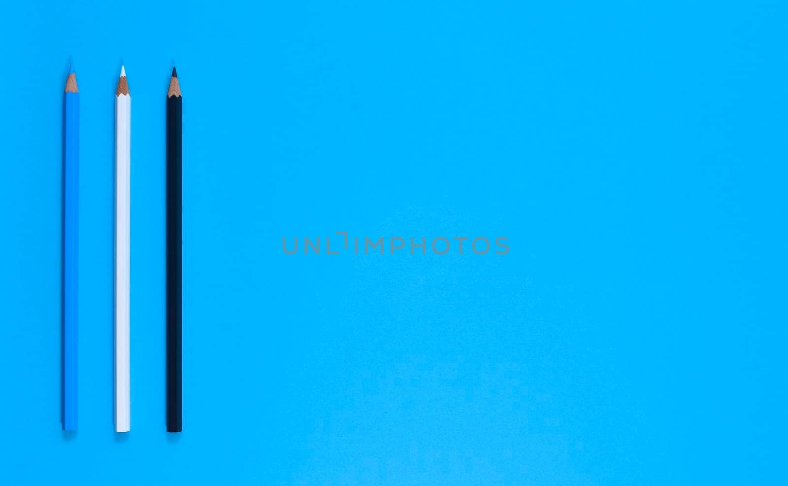 Stationery. Blue, white and black pencil on bright blue background. Top view, flat lay, copy space.