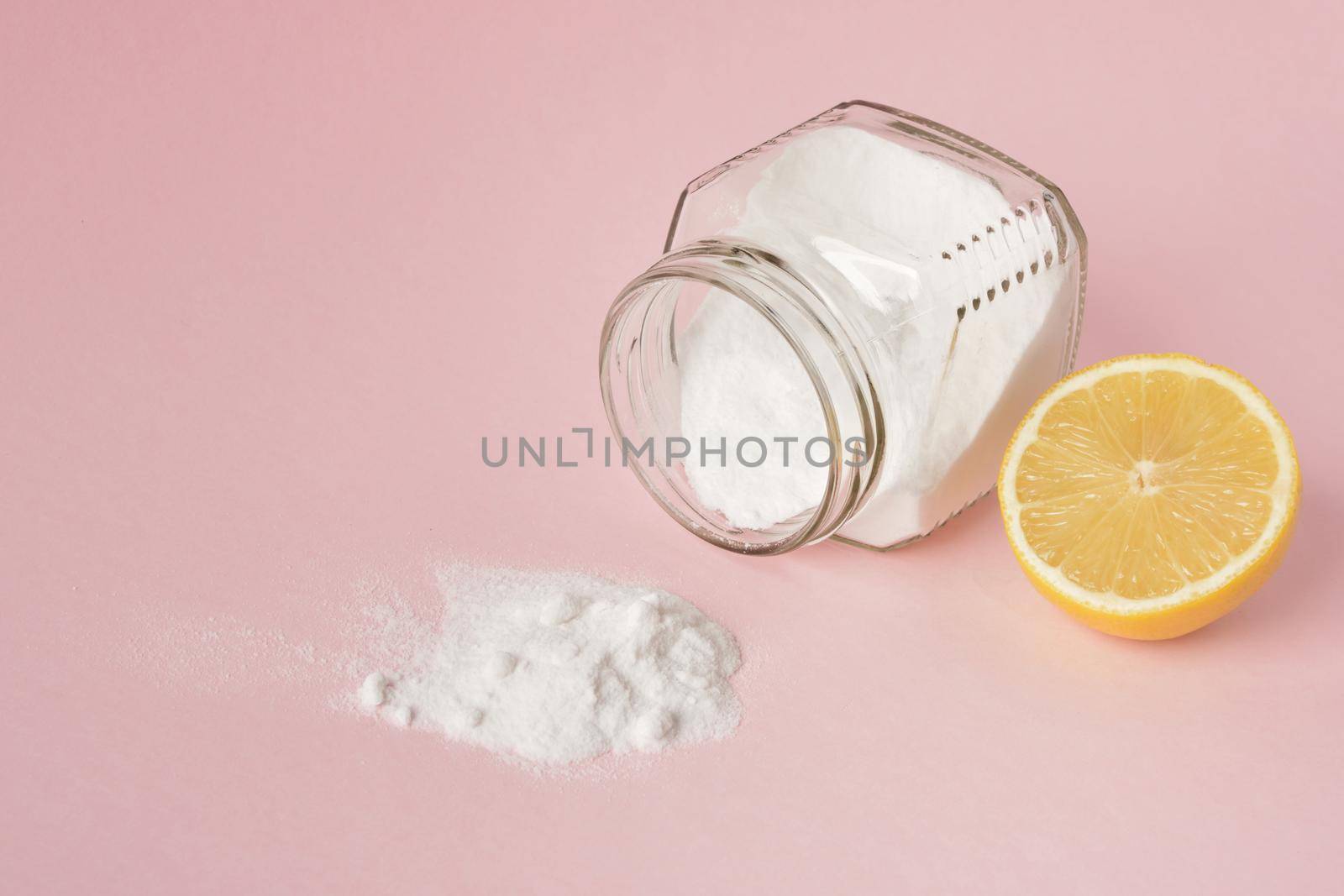 lemon and soda spilled from a glass jar on a pink background