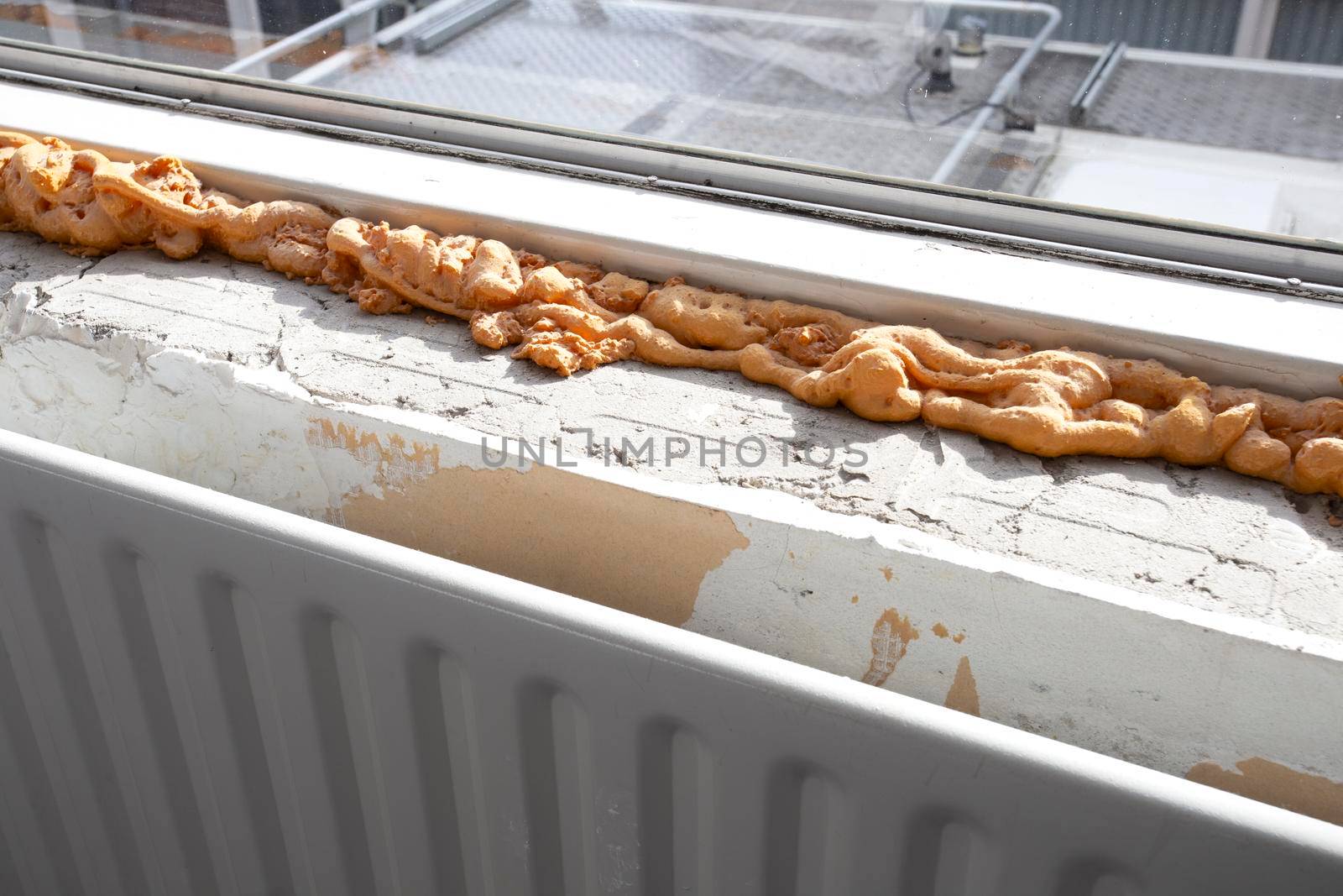 Worker using a polyurethane foam for installation of window sill. Installing window sill restoration,renovation house,building close-up