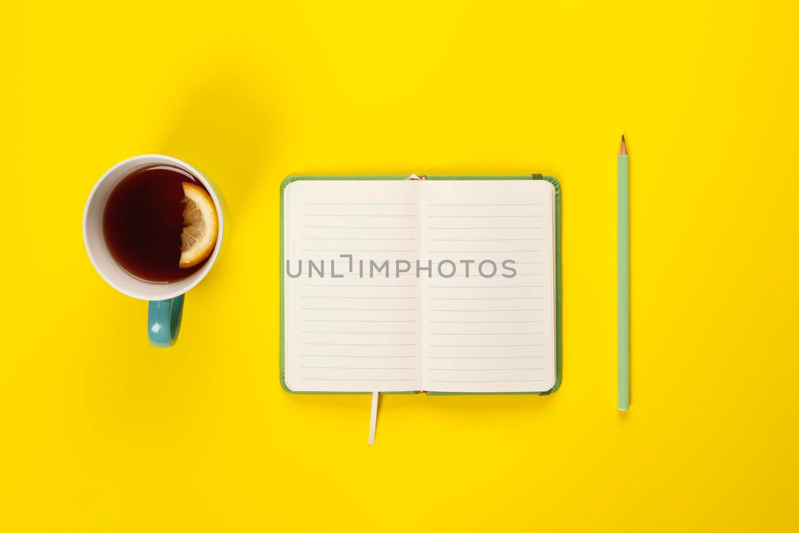 Mint Tea cup and fancy notebook with empty or blank page on bright yellow desk from above, planning and design concept. Top view, flat lay, copy space. Mock up.