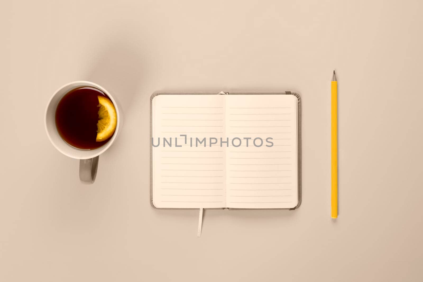 Tea cup and fancy notebook with empty or blank page on desk from above. Mock up toned in trendy 2021 color. by esvetleishaya