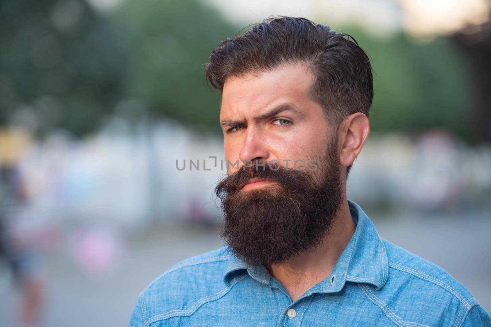 Close-up portrait of serious man model with mustaches and beard in shirt in city
