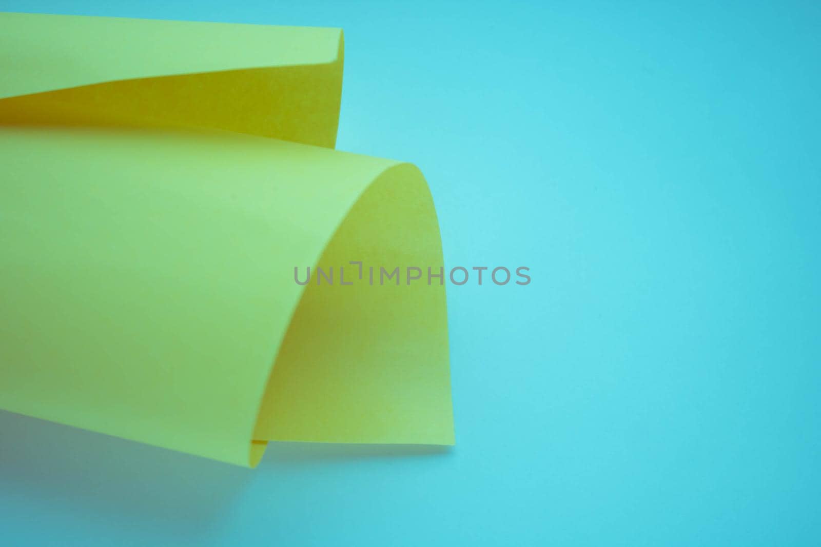 A roll of yellow paper isolated on a blue background.space for text by lapushka62