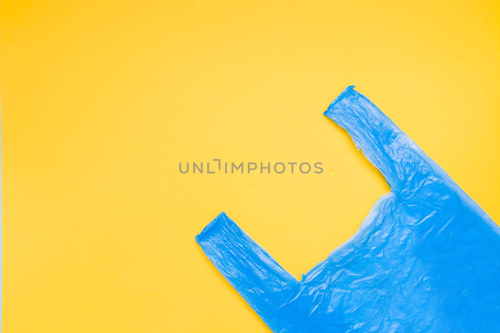 blue plastic bag in the corner on a yellow background, copy space, top view, zero waste concept, nature pollution stop