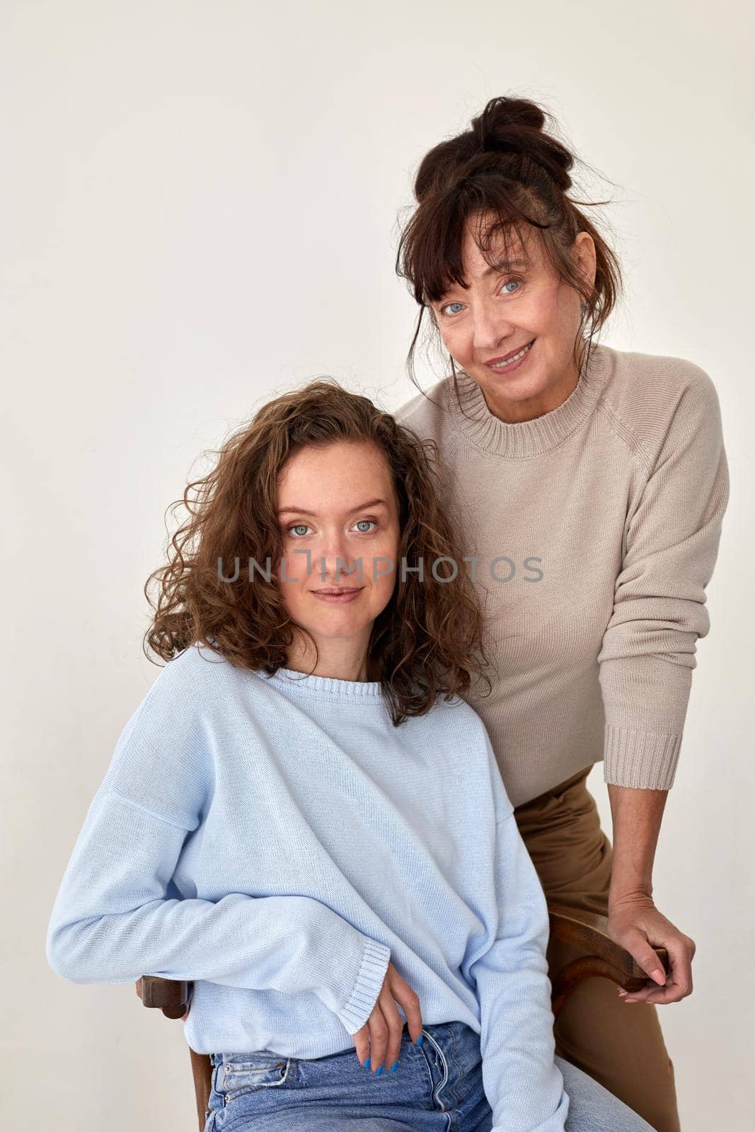 Middle aged and young female models wearing casual warm woolen sweaters looking at camera against white background