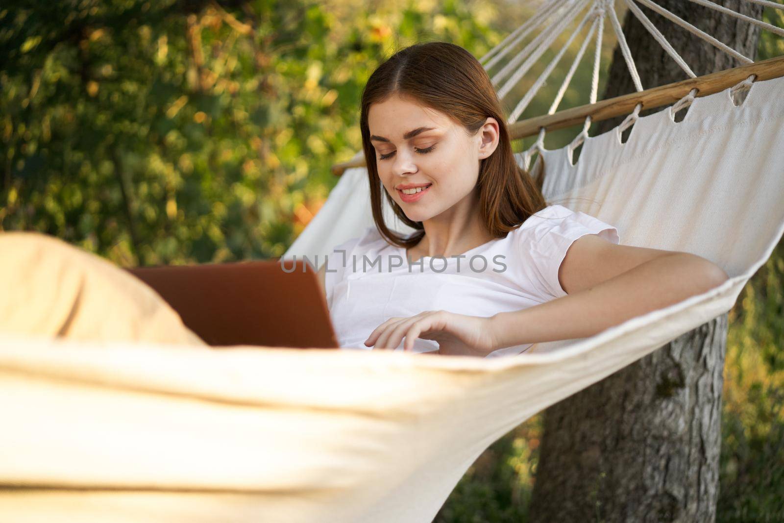 women outdoors lies in a hammock with a laptop freelance internet. High quality photo