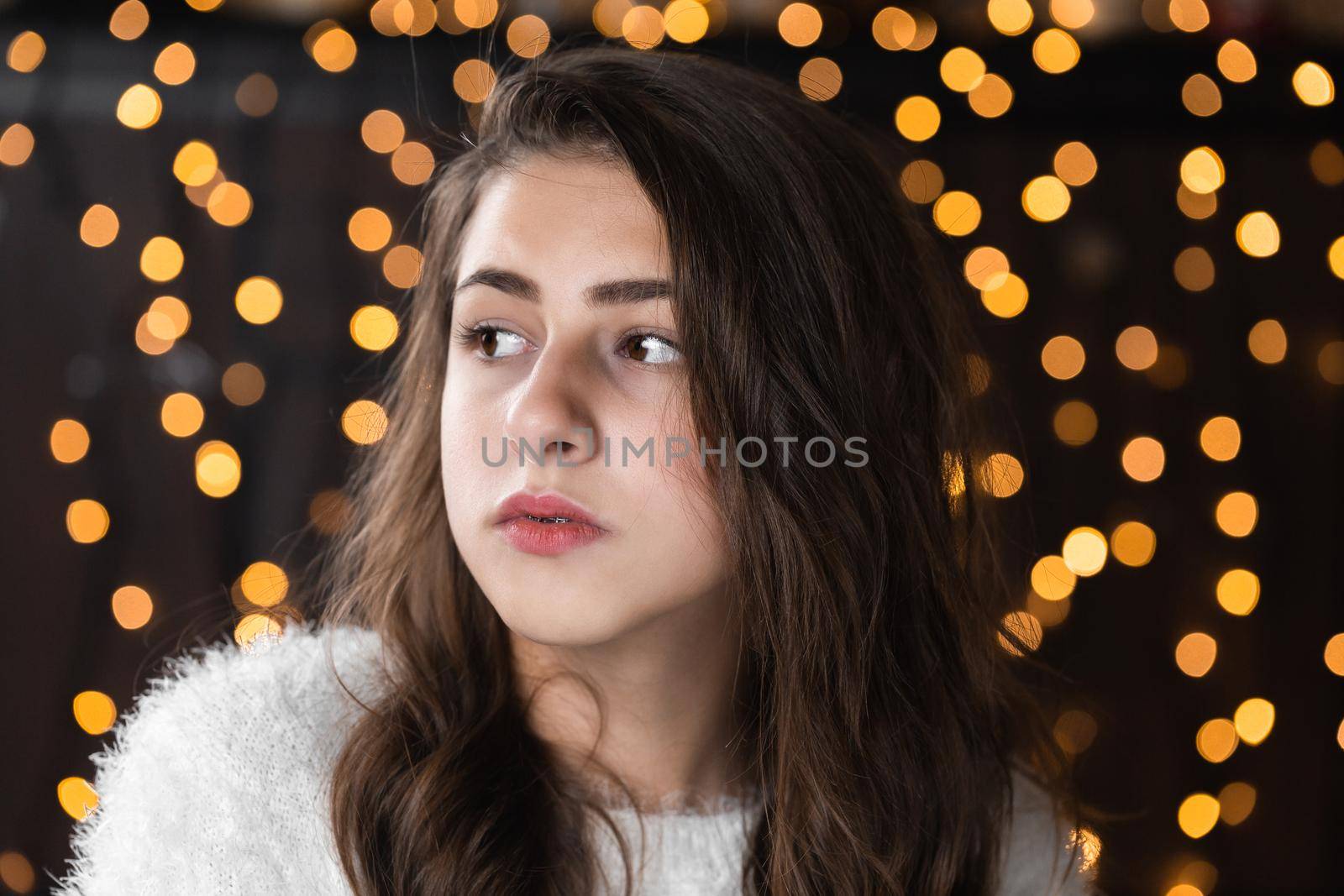 Closeup portrait of very beautiful young woman on christmas bokeh lights background. Attractive female portrait indoors. portrait of pretty woman with warm string lights festive holidays