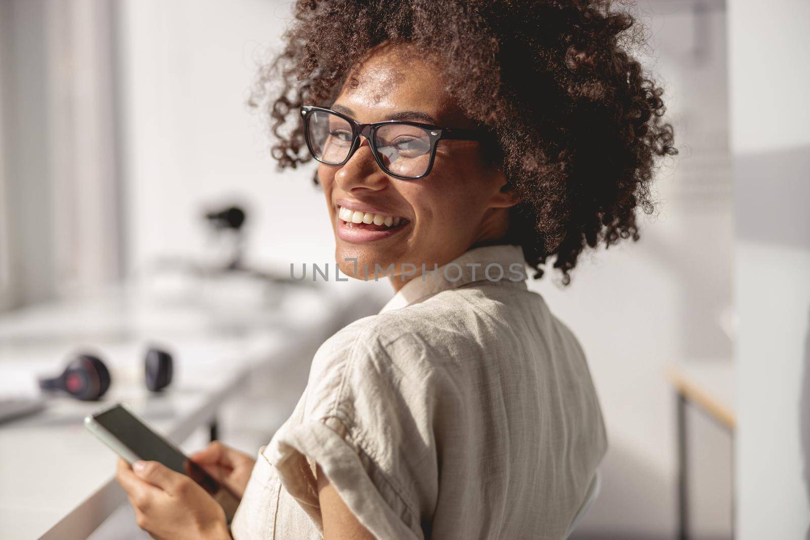 Close up of Afro American worker wearing glasses and using smartphone in the office