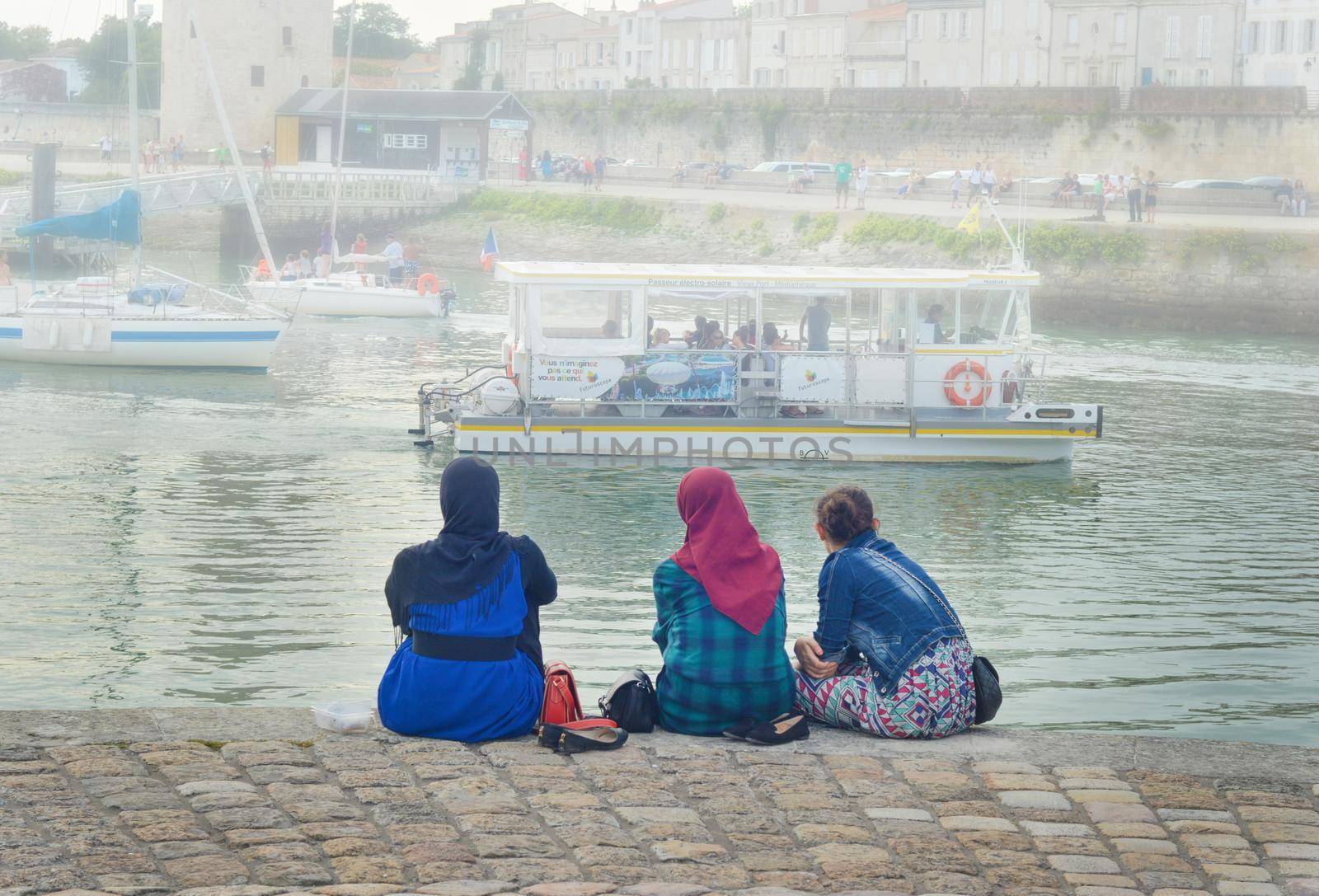 LA ROCHELLE, FRANCE - AUGUST 12, 2015: Muslim woman wearing hijab looking on the ocean Atlantic and yachts at La Rochelle, France.