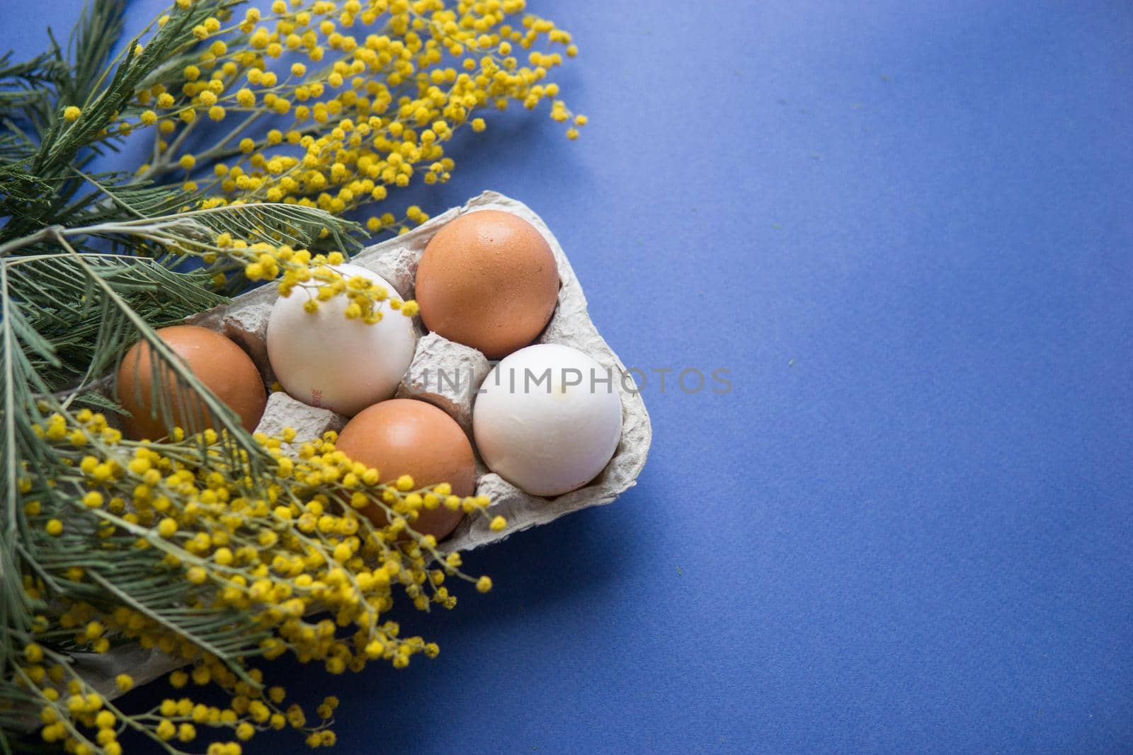 Easter background, eggs on a blue background, decorated with Mimosa flowers, flatlay, top view, empty space for text. happy Easter.