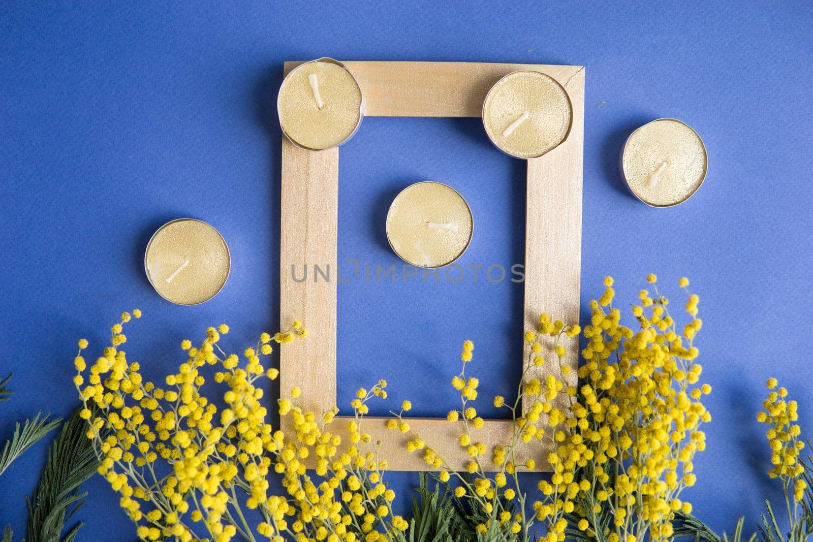 Spring concept, top view. Mimosa and gold frame on blue background. Mimosa close-up. Happy spring. Space for text.