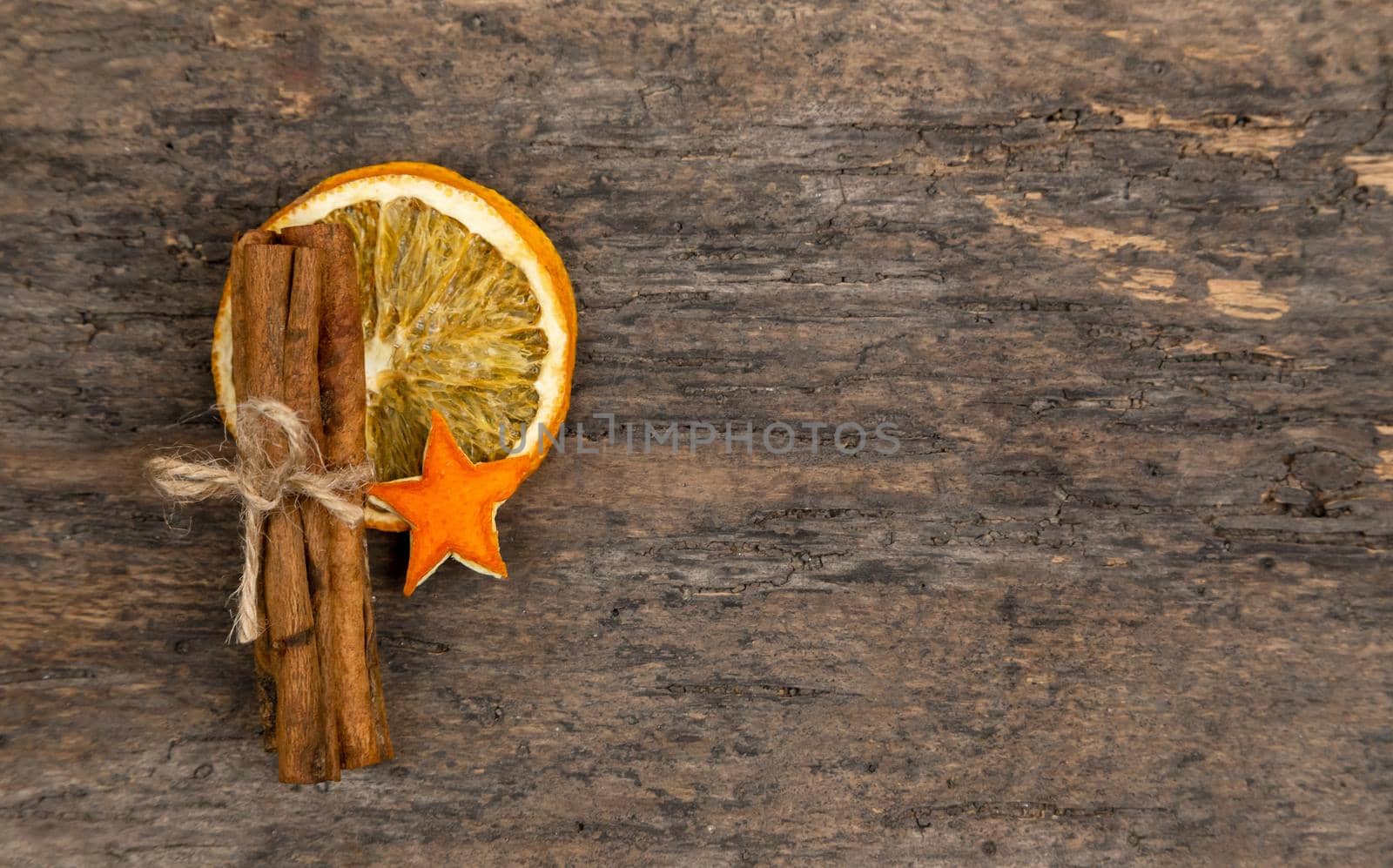 A pile of cinnamon sticks, dried orange and tangerine stars on old wooden table with copy space. Christmas decoration. Christmas card.