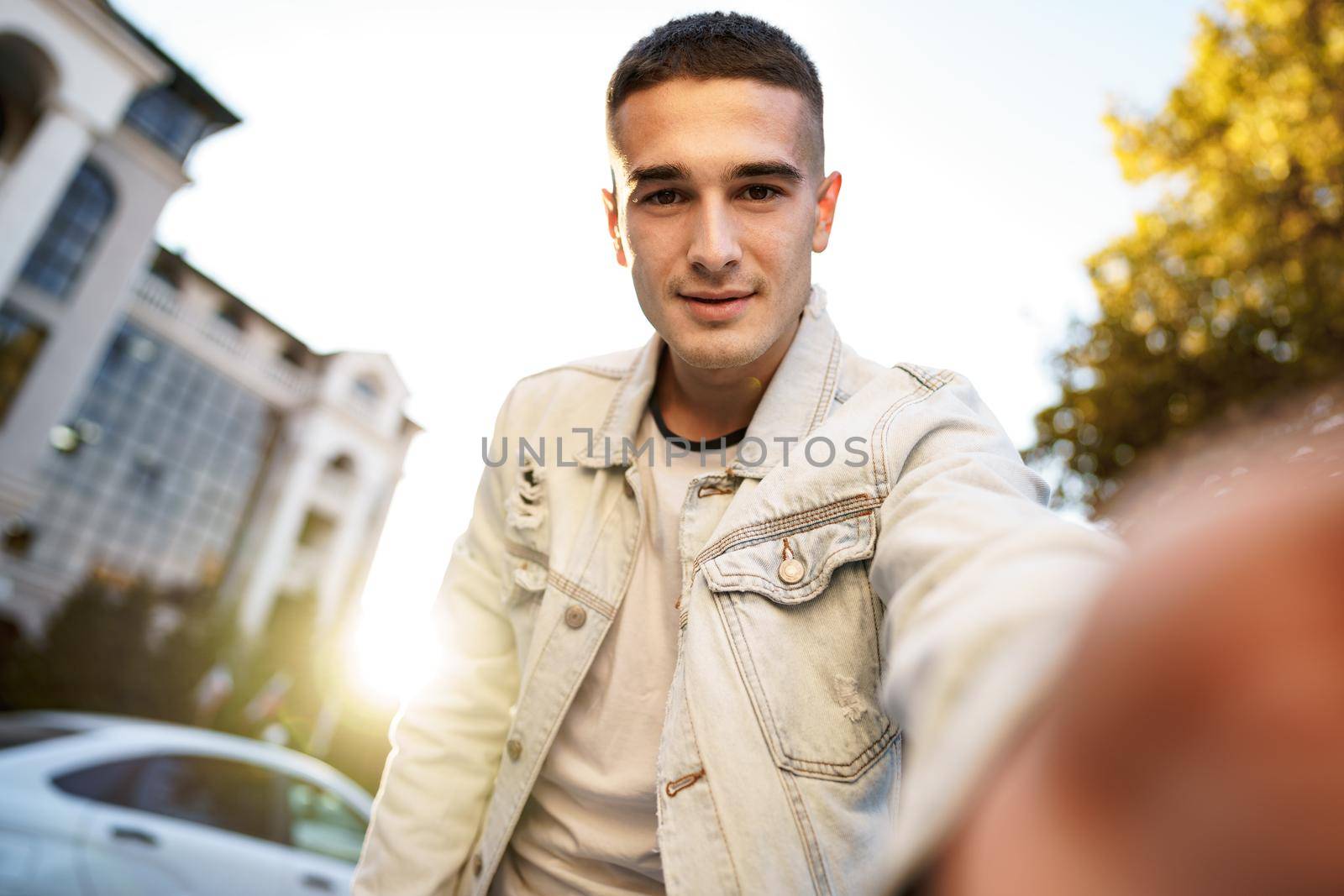 Portrait of young man taking a selfie while out on the city street, close up selfie