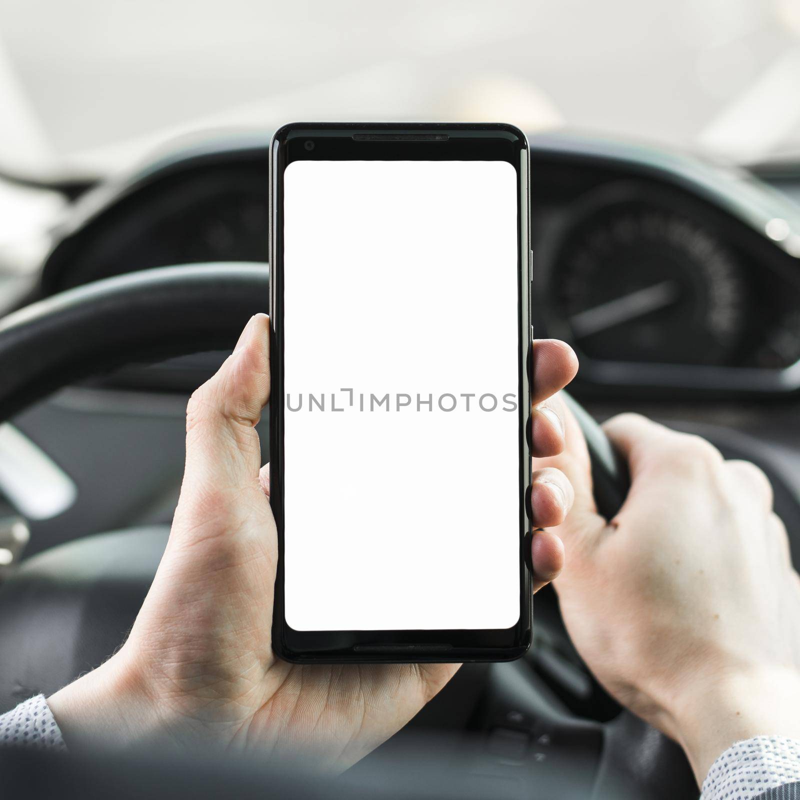 close up man s hand driving car showing blank white screen mobile phone by Zahard