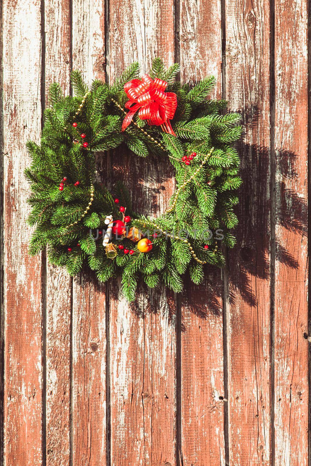 Christmas wreath with decorations on the shabby wooden door.