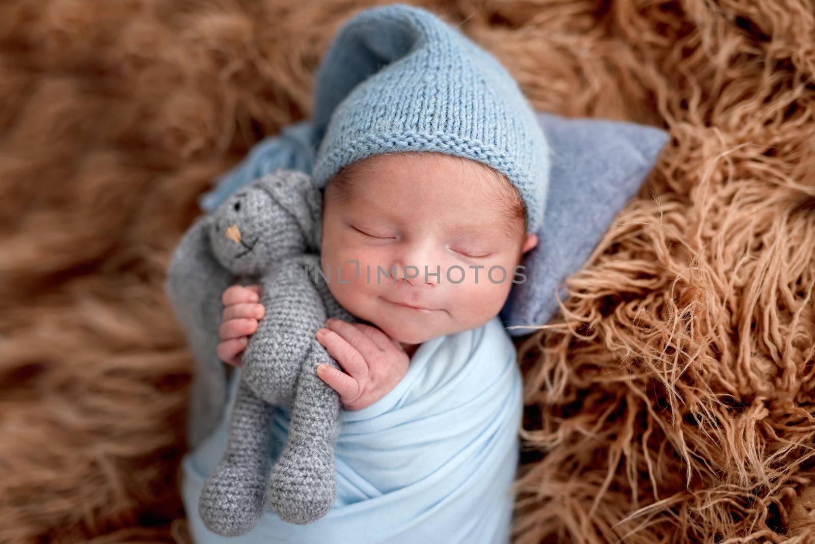 Smiling newborn holding toy while sleeping by tan4ikk1