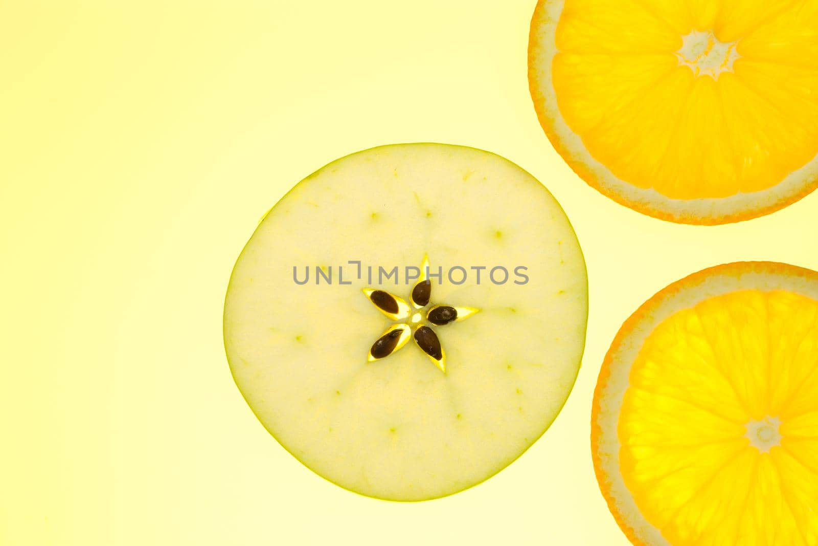 three orange and apple slices on yellow background